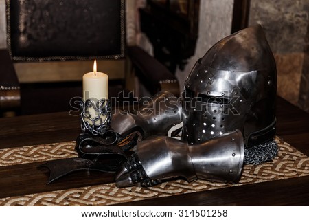 knight\'s helmet with visor and gloves on the table
