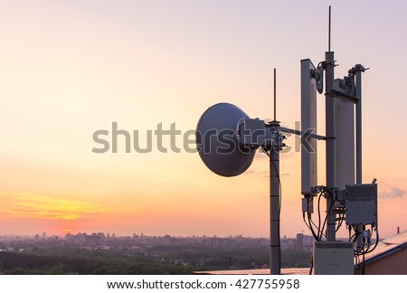 cellular communications tower on a background of the city and a beautiful sunset in summer