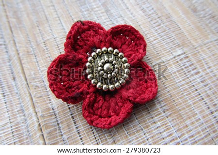 Single knitted poppy flower head. Handmade. Isolated on tissue background. Closeup.