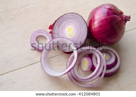 Sliced fresh purple onion isolated on wooden background. Full and chopped onion. Closeup. Yalta onion, cut onion, sliced onion, carved onion, dissected onion, onion peel, onion skins, crimean onion.