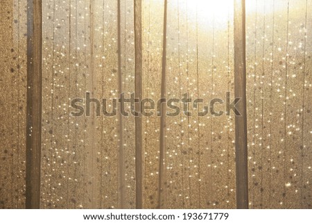 wet glass behind curtain lit by golden sun