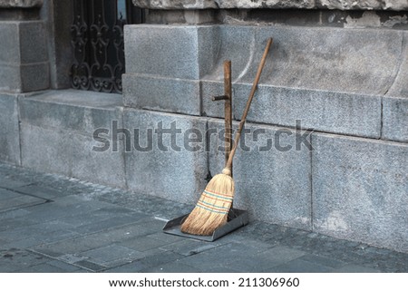 street cleaners broom and shovel next to wall