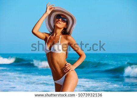 Portrait of sexy beautiful tanned woman posing in colorful swimwear bikini at the sea coast. Exotic country travel and rest concept. Slim figure and sexy body.