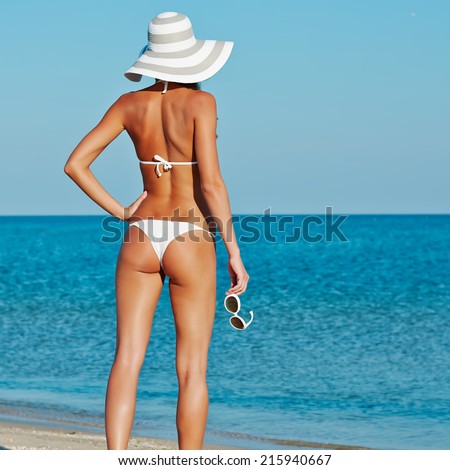 Sexy beautiful woman in white bikini and hat with creative white sunglasses on sea background.