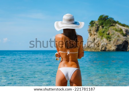 Sexy beautiful woman in white bikini with creative white sunglasses on Mediterranean sea coast