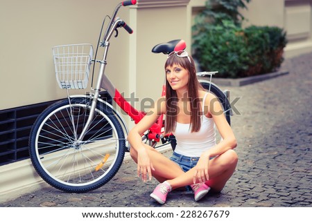 Young pretty sexy woman retro hipster style outdoor portrait with with red bicycle has fun and smiling