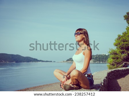 Beautiful young woman looking and waiting at the seacoast. Sunny day. Montenegro, Europe. Retro style toning image.
