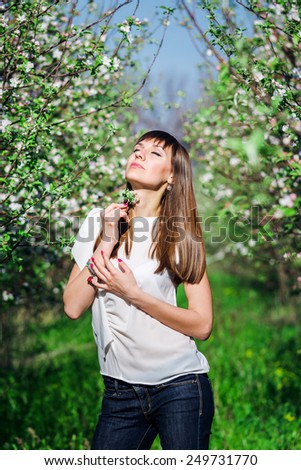 Beautiful smiling girl near blossom apple tree with white flowers in spring garden with green grass
