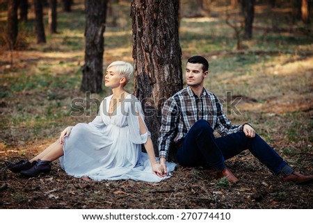 Outdoor lifestyle portrait of young couple hugging in pine forest. Sunny warm weather. Retro vintage toned image, film simulation.
