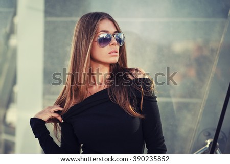 Beautiful brunette young woman in nice black dress, sunglasses. Fashion Photo