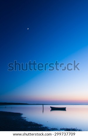 Mystical sea. Abstract natural backgrounds. Moon scene after sunset with still water and vintage boat.