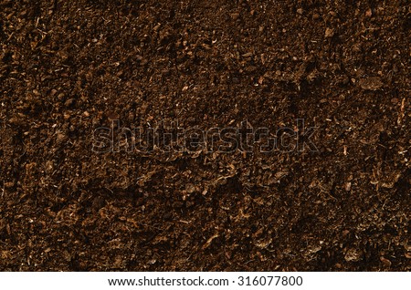 Brown, fertile, sandy soil ready for planting or fertilizing. Camera from above, top view. Natural background for advertisements.