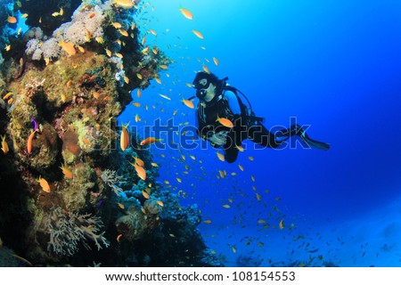 Underwater image of female Scuba Diver with tropical fish on a coral reef