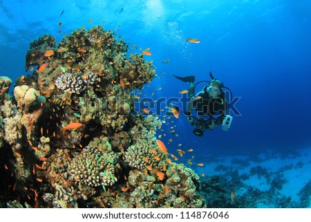 Underwater Photographer scuba diving with camera on coral reef in ocean