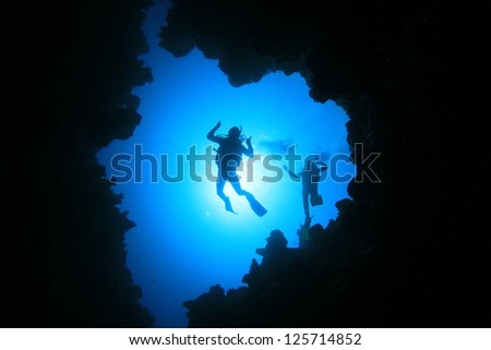 Couple of Scuba Divers descend into an underwater cavern