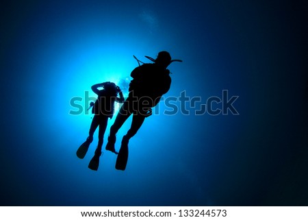 Two Scuba Divers Underwater Silhouettes Against Sun