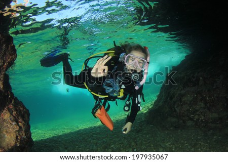 Young Woman Scuba diving into underwater cave