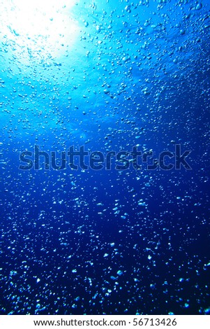 Air bubbles float up through blue sea water