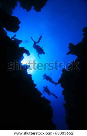 Scuba Divers descend into an underwater cavern