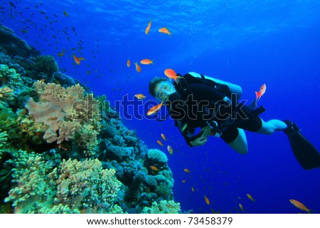 Young Woman Scuba Diver on coral reef in clear blue water