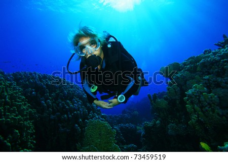 Young woman scuba diving on a coral reef in the Red Sea