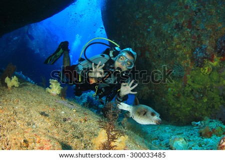 Woman scuba diver exploring underwater cavern and puffer fish