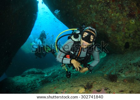 Female scuba diver exploring coral reef underwater with fish
