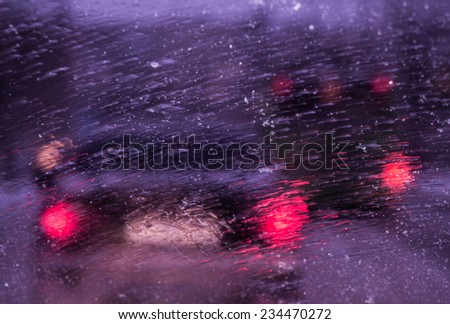 City road through molten snow and water drops on the car windshield