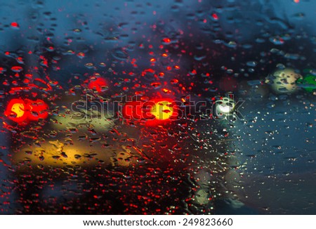 Blurry car silhouette seen through raindrops on the car windshield