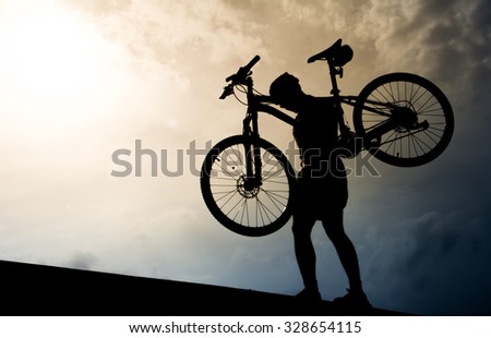 A man with mountain bicycle lifted above him. Silhouette style.