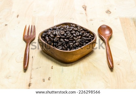 coffee beans with wooden cup and wooden spoon and wooden fork on wooden background.