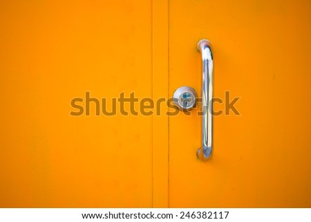 the handle and its lock on the yellow steel door.