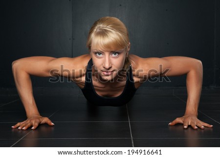 Beautiful athletic woman is pushed up on  a dark background