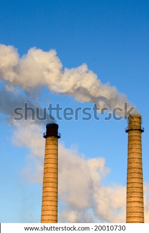 Brick pipes with a smoke on a background of the clear blue sky