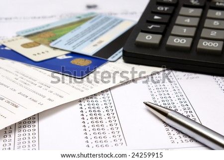 Heap of bills and checks, credit cards, the calculator, a ball pen.