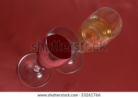 two wineglasses with different wines on red cover