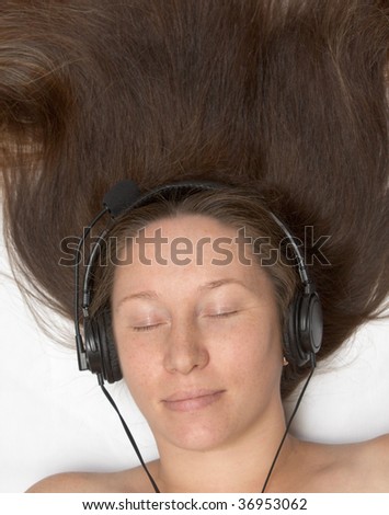 The woman lays and listens to music. Long hair lay upwards.