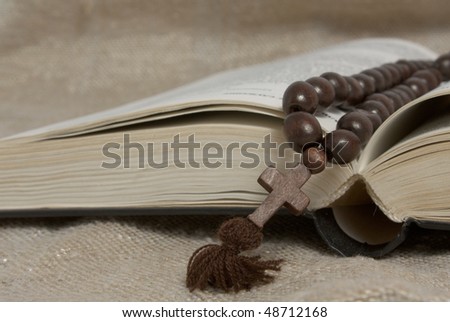 black opened bible and wooden cross on rustic canvas