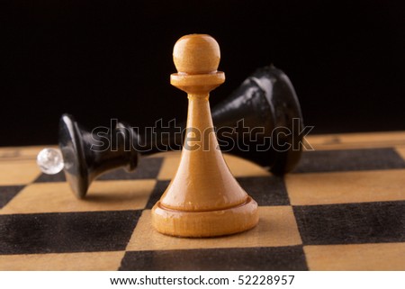 black chess queen lays on a chessboard, black background