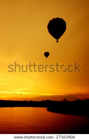 A trio of balloons flying into the setting sun