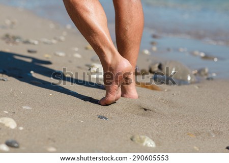 Man walking on sand beach, male legs at sand summer vacation, man fit at ocean water in sunset light. Man running on the beach at sunset.