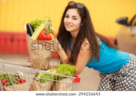 Shopping young woman in store with bags of vegetables, happy girl in supermarket, female customer at market buying vegetables, woman holding shopping basket in supermarket, instagram style filters
