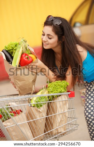 Shopping young woman in store with bags of vegetables, happy girl in supermarket, female customer at market buying vegetables, woman holding shopping basket in supermarket, instagram style filters
