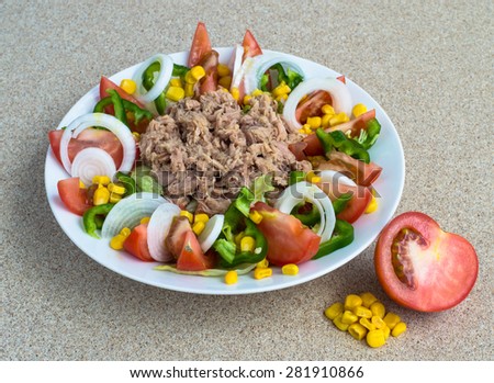 Spanish mixed salad. Vegetables: lettuce,tomato, green pepper, onion and corn with tuna meat from a tin in the middle. All seasoned with salt, olive oil and vinaigrette, white plate. Missing olives.