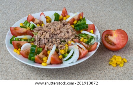 Spanish mixed salad. Vegetables: lettuce,tomato, green pepper, onion and corn with tuna meat from a tin in the middle. All seasoned with salt, olive oil and vinaigrette, white plate. Missing olives.