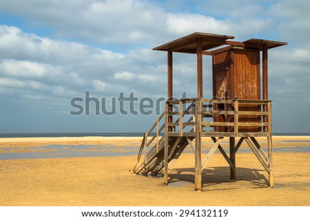 Empty lifeguard booth on a cloudy day on one of Andalusian beaches on the Coast of Light (Costa de la luz) in Spain. Lonely, abandoned  wooden lifeguard shed, empty beach, golden sand, pacific ocean.