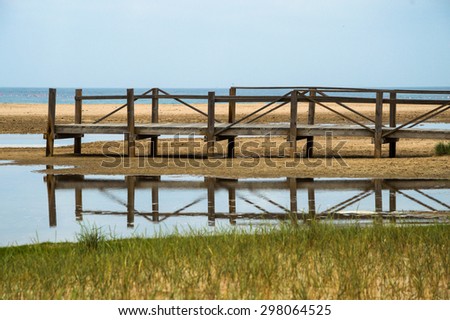 Wooden platform on the flooded beach in Tarifa, Spain. Atlantic ocean in the background. Platform reflections in the water.