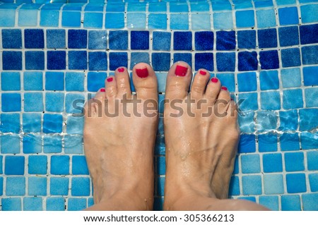 Feet in the swimming pool. Relax, vacation, summer. Red nails, suntanned skin, turquoise water. Sunlight dancing in the water. Blue tiles on the bottom of the swimming pool. Summer holidays. Enjoyment