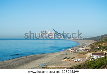 Alcaidesa beach with rock of Gibraltar in the background. Morning, calm Mediterranean sea, empty beach. Rock of Gibraltar on the horizon. Colorful sunbeds, bar, shower. Rule of thirds. Nice landscape.