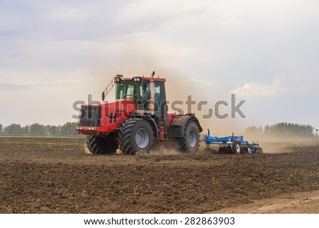 Color photo of a red tractor against the blue sky.
